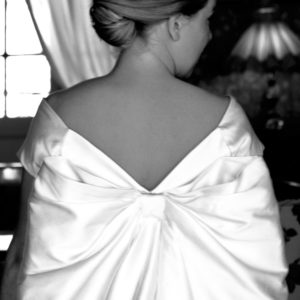 CATHERINE - Robe de mariée en mikado coton et soie, corsetée décolletée sur les épaules avec jupe à plis creux fermés. Ceinture brodé et traine amovible en noeud.